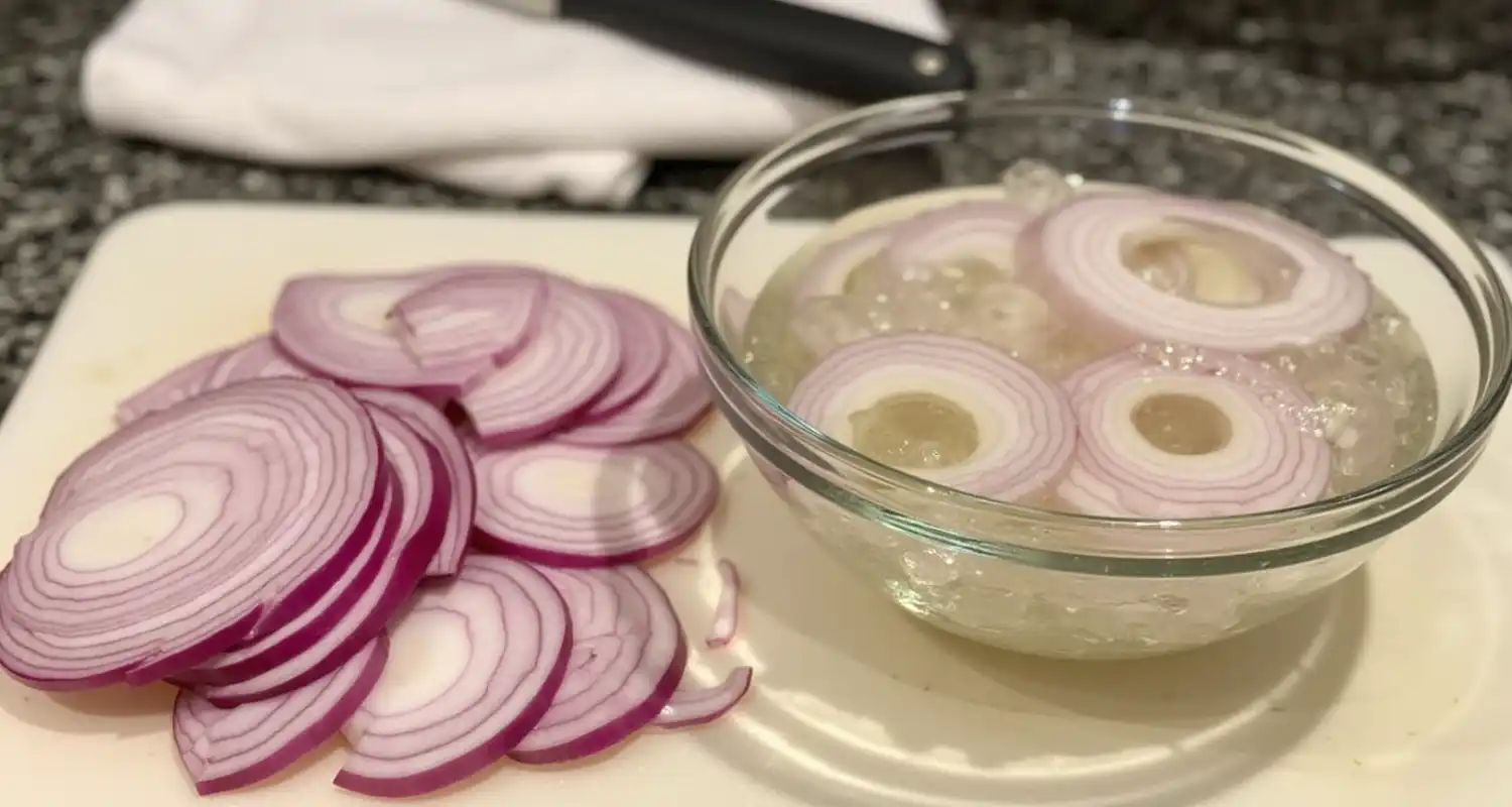 Thinly sliced red onions soaking in ice water to reduce sharpness